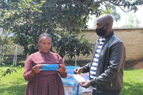 A women’s saving group representative receiving a face mask donated by AAR in partnership with FVA 